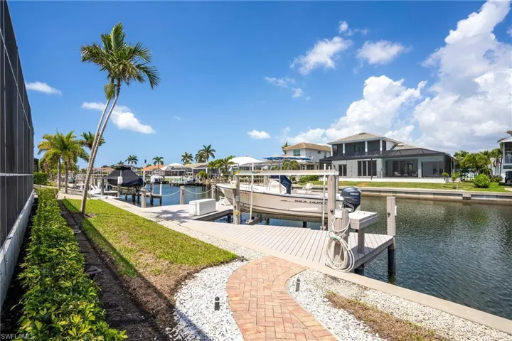 View of dock featuring boat lift, a residential view, a water view, and a lanai