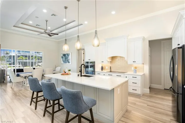 Kitchen with premium range hood, tasteful backsplash, a ceiling fan, a tray ceiling, and freestanding refrigerator