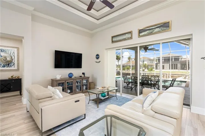 Living area featuring baseboards, ornamental molding, light wood-style flooring, and a ceiling fan
