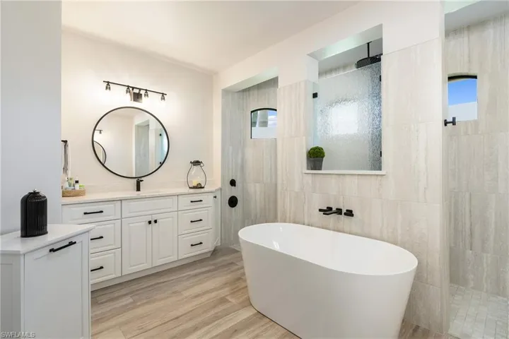 Full bathroom with tile walls, a freestanding bath, a walk in shower, and vanity