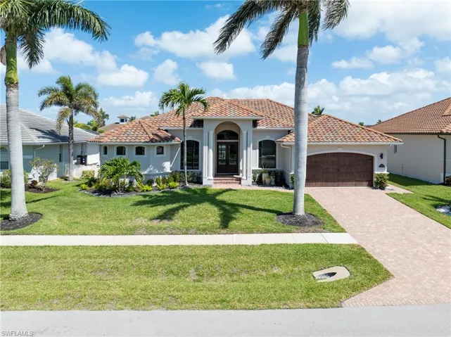Mediterranean / spanish home featuring stucco siding, an attached garage, a tiled roof, decorative driveway, and a front lawn