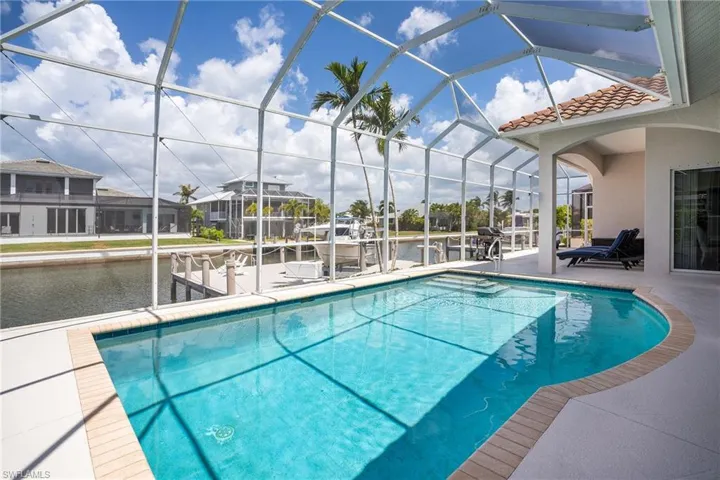 Outdoor pool featuring a dock, glass enclosure, and a patio area