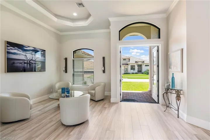 Foyer entrance featuring light wood-type flooring, a wealth of natural light, crown molding, and visible vents
