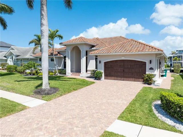Mediterranean / spanish-style home with a tiled roof, stucco siding, an attached garage, and a front lawn