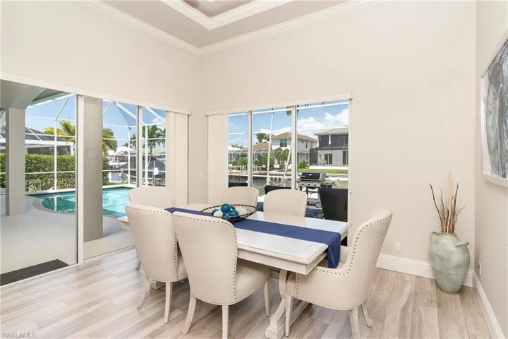 Dining room with ornamental molding, a sunroom, baseboards, and light wood finished floors