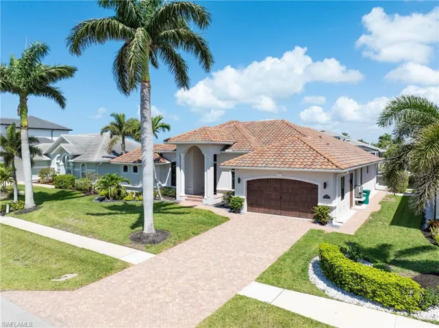 Mediterranean / spanish home featuring driveway, stucco siding, a front lawn, a tiled roof, and a garage