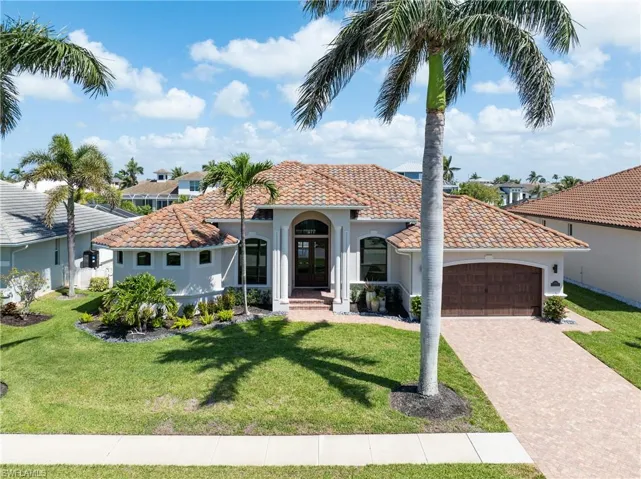 Mediterranean / spanish-style house with driveway, an attached garage, a tiled roof, and a front yard