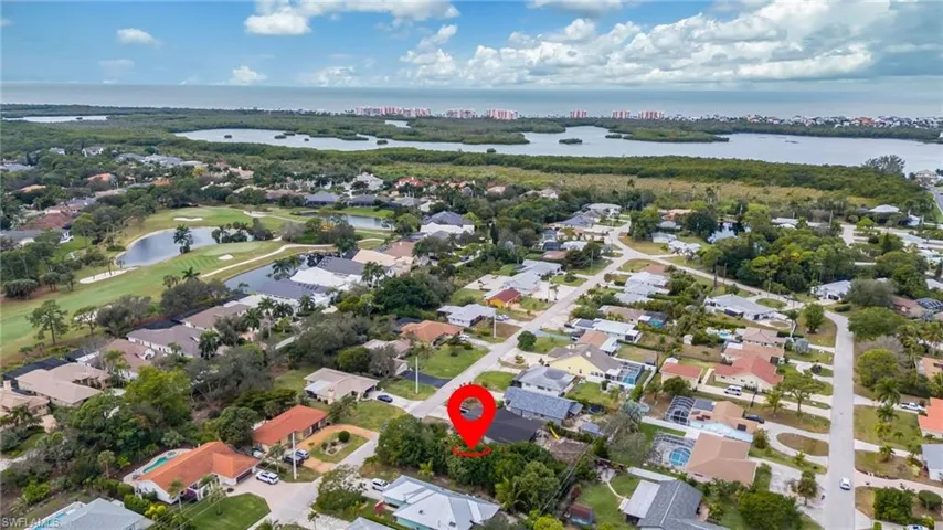 Aerial overview of property's location with a large body of water, nearby suburban area, and a golf club