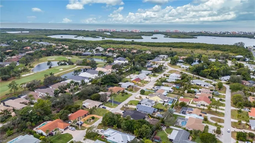 Aerial overview of property's location with a nearby body of water, nearby suburban area, and a golf course