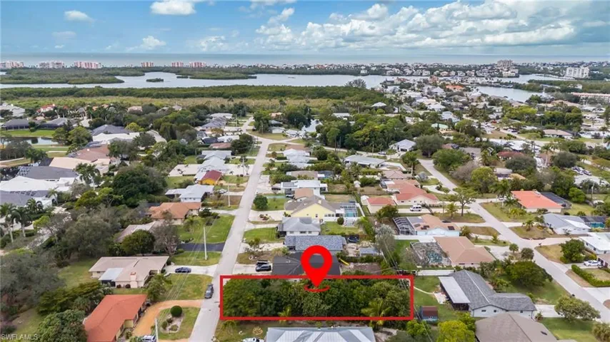 Aerial view of property's location featuring property parcel outlined, a nearby body of water, and nearby suburban area