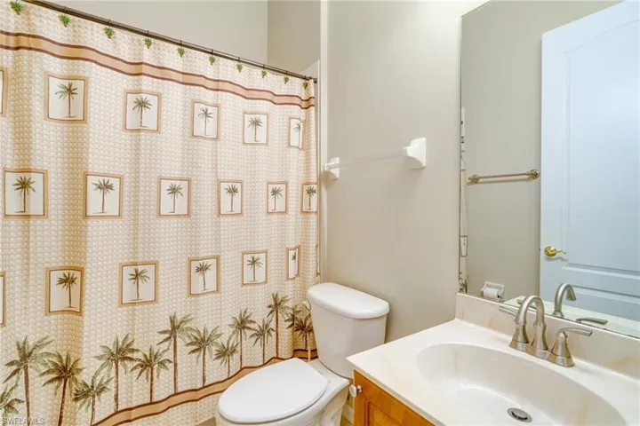 Bathroom with toilet, a shower with shower curtain, and vanity