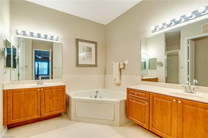 Full bath with a stall shower, two vanities, a garden tub, and a sink