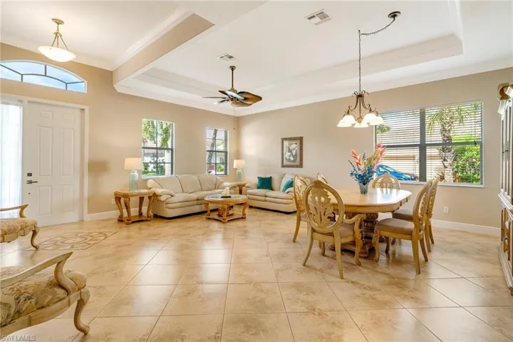 Dining space with light tile patterned floors, visible vents, and a raised ceiling