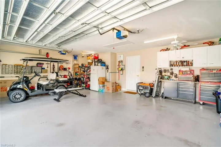 Garage featuring a garage door opener, freestanding refrigerator, and a workshop area