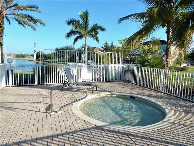 View of pool featuring a community hot tub, a water view, and fence