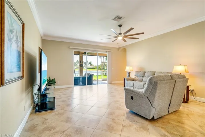 Living room with baseboards, visible vents, arched walkways, and crown molding