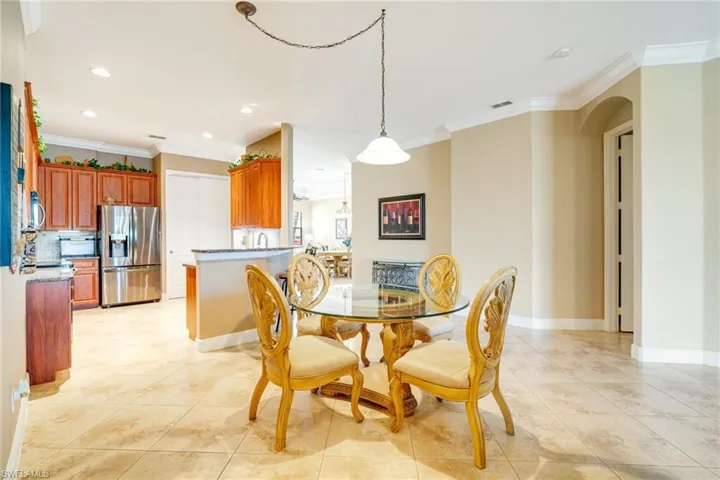 Dining area with arched walkways, light tile patterned floors, visible vents, and crown molding