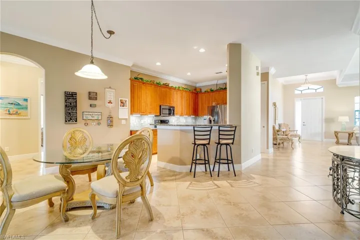 Dining room featuring ornamental molding, arched walkways, baseboards, and light tile patterned floors