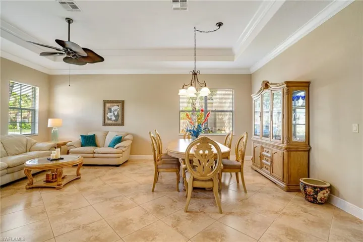 Dining space featuring baseboards, visible vents, a raised ceiling, and crown molding