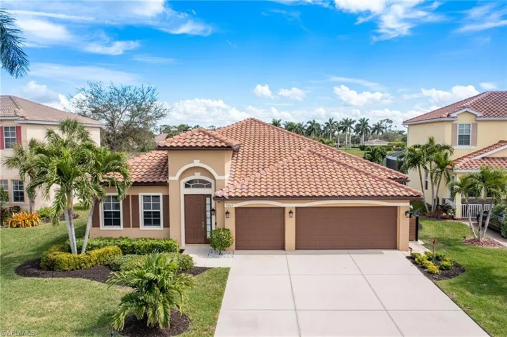Mediterranean / spanish home with a garage, driveway, stucco siding, a tile roof, and a front yard