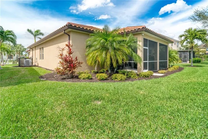 View of side of property with a sunroom, a tile roof, a lawn, and stucco siding