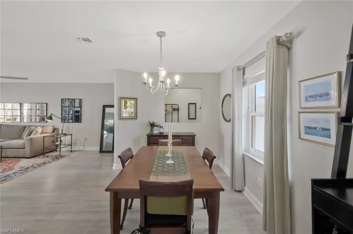 Dining area featuring visible vents, a notable chandelier, light wood-style flooring, and baseboards