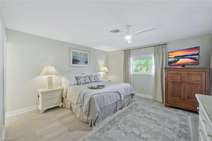 Primary bedroom with luxury vinyl flooring, ceiling fan and access to the primary bathroom and sliding door access to the lanai (not shown).