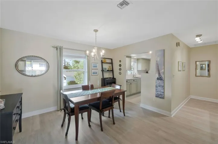 Dining room with chandelier, luxury vinyl flooring and access to the kitchen.