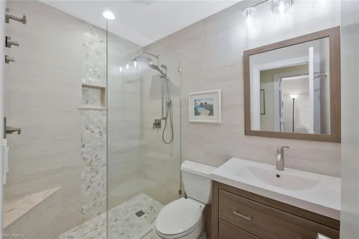 Guest bathroom with walk-in shower, custom tile, vanity and toilet.