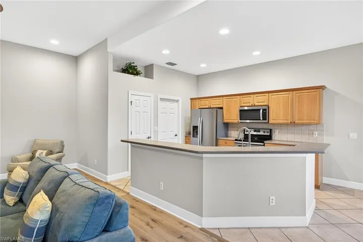 Kitchen featuring decorative backsplash, recessed lighting, stainless steel appliances, open floor plan, and dark stone counters