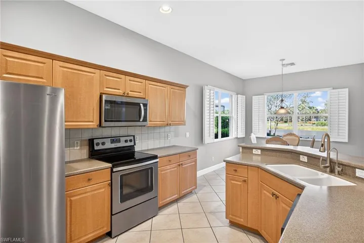 Kitchen featuring appliances with stainless steel finishes, light tile patterned floors, decorative light fixtures, backsplash, and recessed lighting