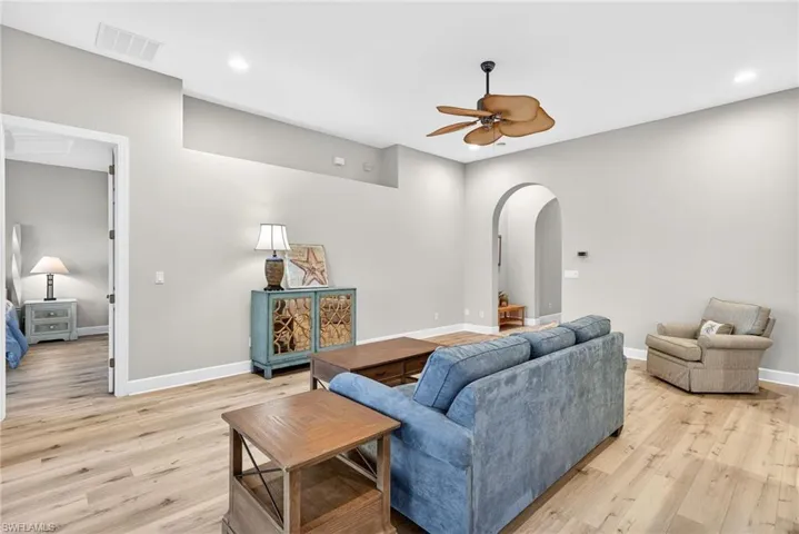 Living area with arched walkways, recessed lighting, ceiling fan, and light wood finished floors