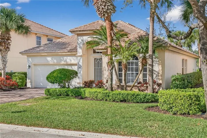 Mediterranean / spanish home with stucco siding, a garage, driveway, a front lawn, and a tiled roof