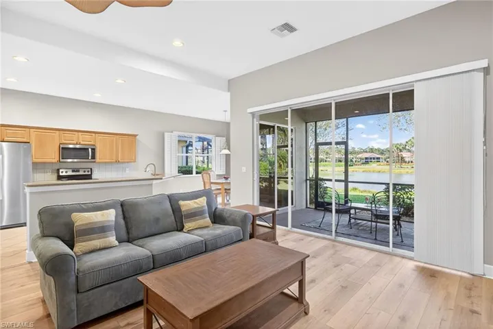 Living room featuring light wood-type flooring, recessed lighting, a water view, and a ceiling fan