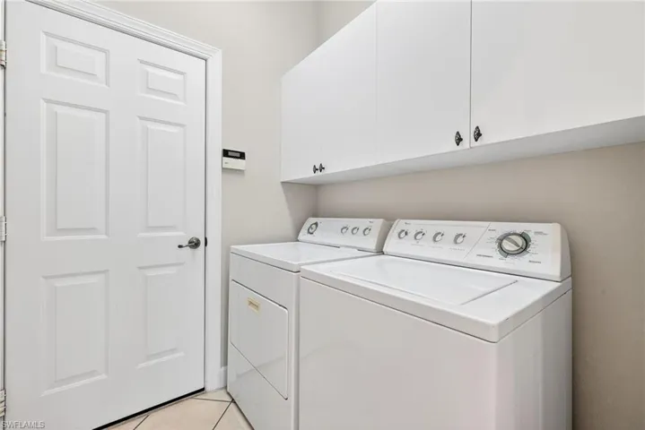 Washroom featuring cabinet space, separate washer and dryer, and light tile patterned floors
