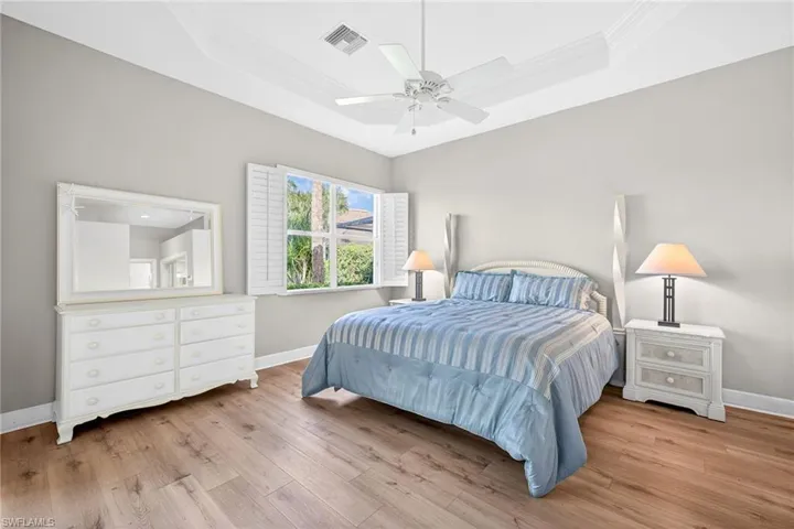 Bedroom featuring a tray ceiling, light wood-type flooring, a ceiling fan, and ornamental molding