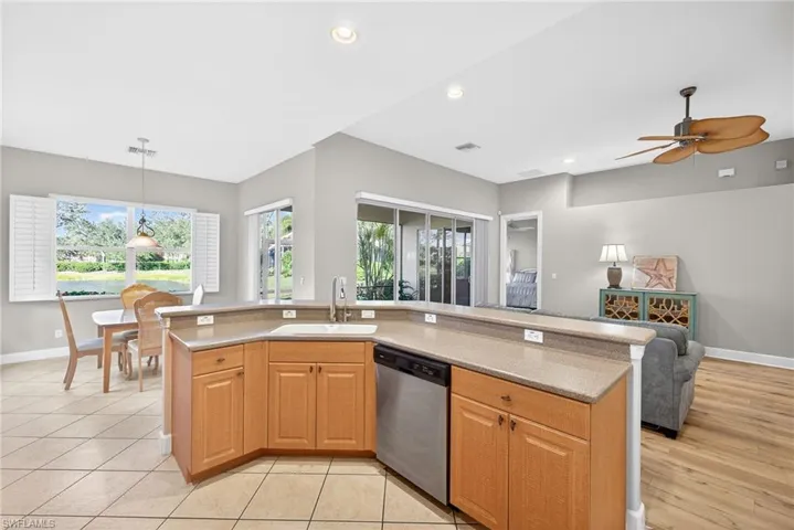 Kitchen with a center island with sink, open floor plan, stainless steel dishwasher, hanging light fixtures, and healthy amount of natural light