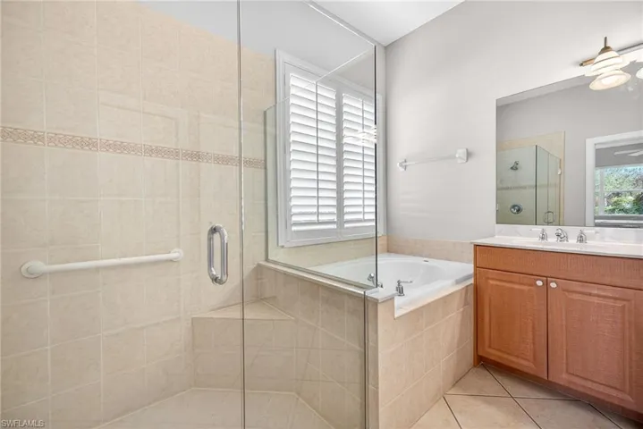 Full bath featuring vanity, light tile patterned floors, a bath, and a stall shower