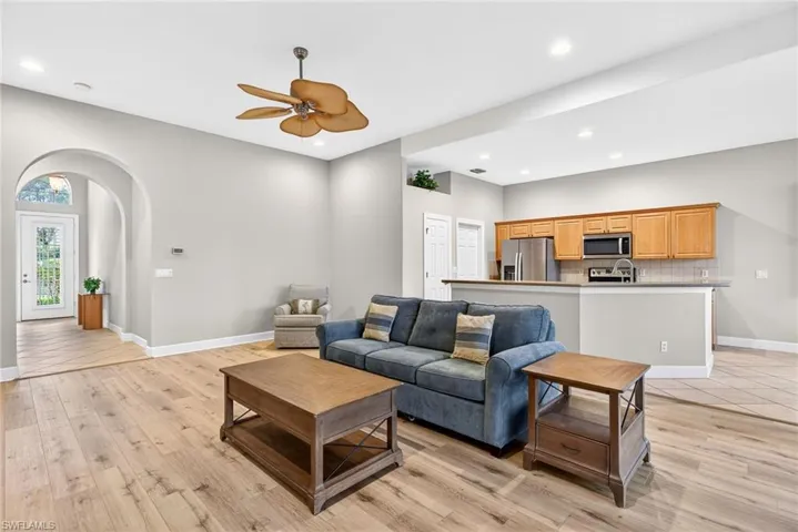 Living room featuring arched walkways, a ceiling fan, recessed lighting, and light wood finished floors