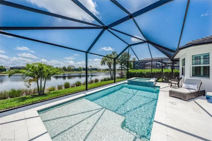 View of swimming pool featuring an in ground hot tub, a water view, a lanai, and a patio