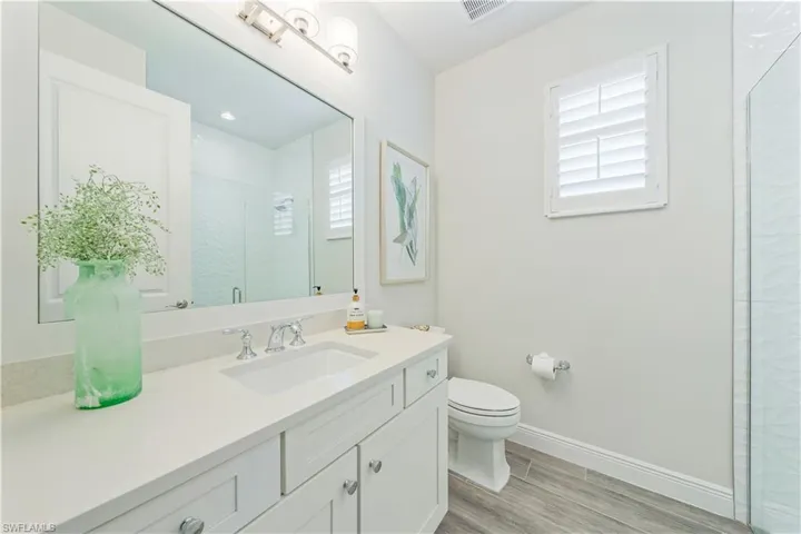 Bathroom with an enclosed shower, vanity, and toilet