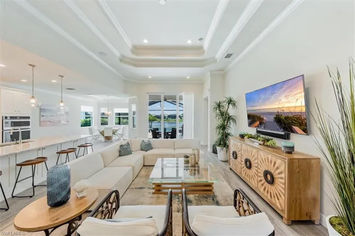 Living room with light hardwood / wood-style floors, ornamental molding, a raised ceiling, and a high ceiling