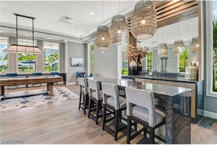 Bar featuring crown molding, decorative light fixtures, billiards, and light hardwood / wood-style flooring