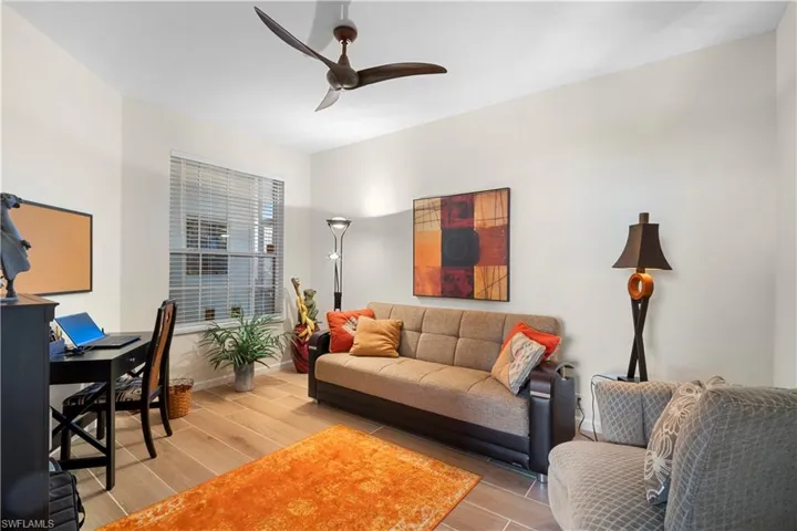 Living room featuring wood tiled floors, a ceiling fan, and a desk