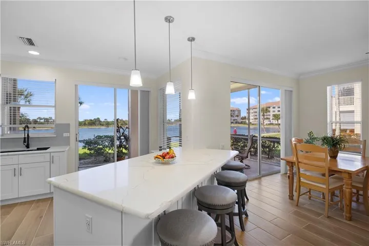 Kitchen with white cabinets, a breakfast bar area, crown molding, wood tiled floors, and plenty of natural light