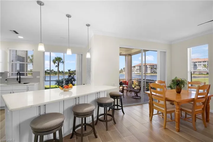 Kitchen featuring white cabinets, a breakfast bar, wood finish floors, ornamental molding, and plenty of natural light