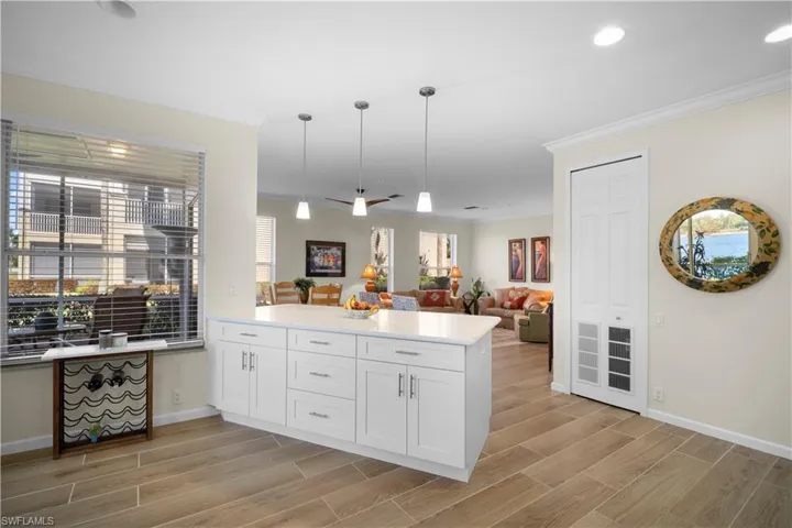 Kitchen with open floor plan, wood finish floors, light stone counters, crown molding, and a peninsula