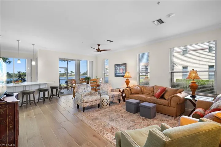 Living area featuring ornamental molding, light wood finished floors, plenty of natural light, and ceiling fan