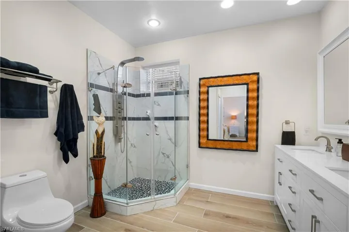 Bathroom with wood finish floors, double vanity, and a marble finish shower