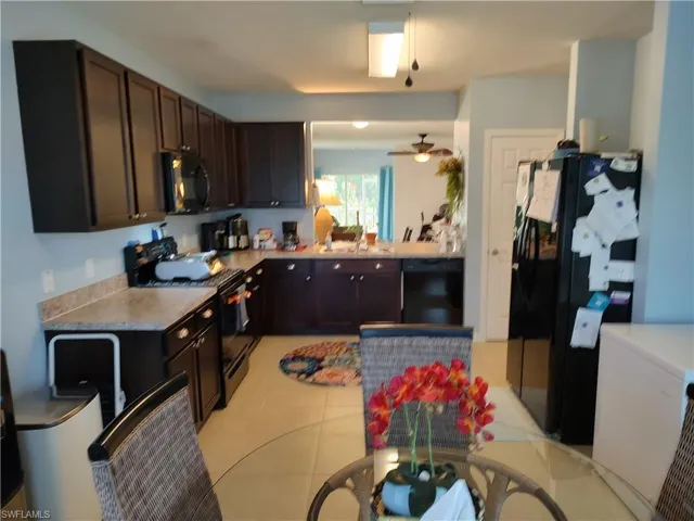 Kitchen with light tile floors, black appliances, ceiling fan, and dark brown cabinets